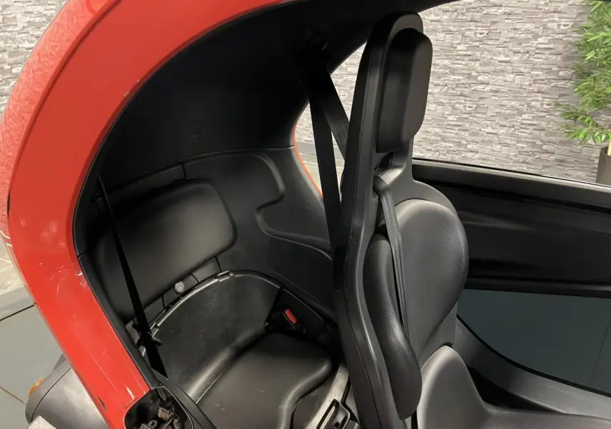 Vue intérieure côté droit du Renault Twizy orange 2019, montrant les sièges noirs compacts et la ceinture de sécurité.