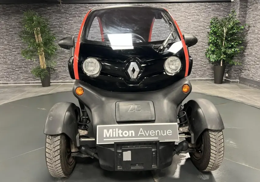 Vue de face d'une Renault Twizy Intens 2019 orange avec logo Renault et feux ronds dans un showroom.