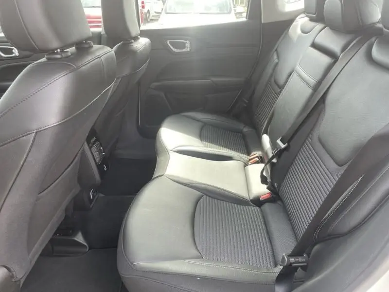 Vue intérieure arrière du Jeep Compass 2024, sièges en cuir noir avec surpiqûres et ceintures de sécurité visibles.