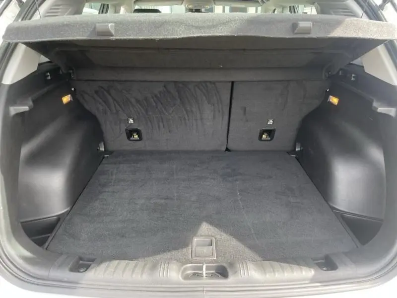 Coffre ouvert en vue arrière d'un Jeep Compass blanc 2024, espace de chargement propre et tapis noir visible.