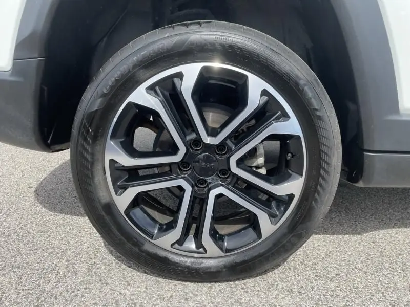 Gros plan sur la roue avant droite du Jeep Compass blanc 2024, jante alliage bicolore au design moderne.
