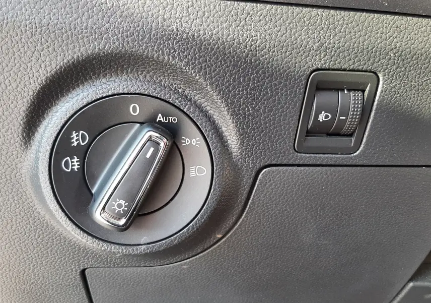 Gros plan sur le bouton de commande des phares et réglage d'intensité dans l'habitacle gris du SEAT Arona 2019.