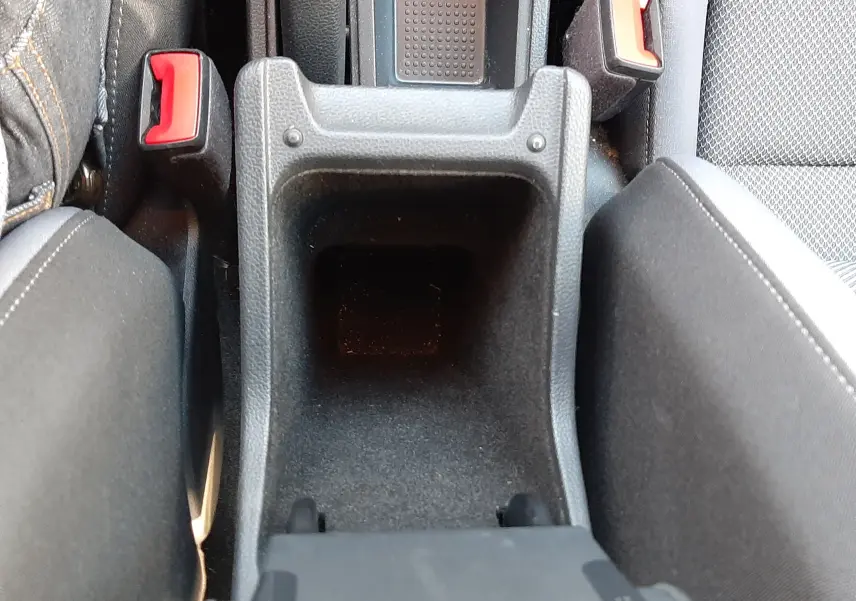 Vue plongeante sur le rangement central noir entre les sièges avant gris tissu du SEAT Arona 2019.