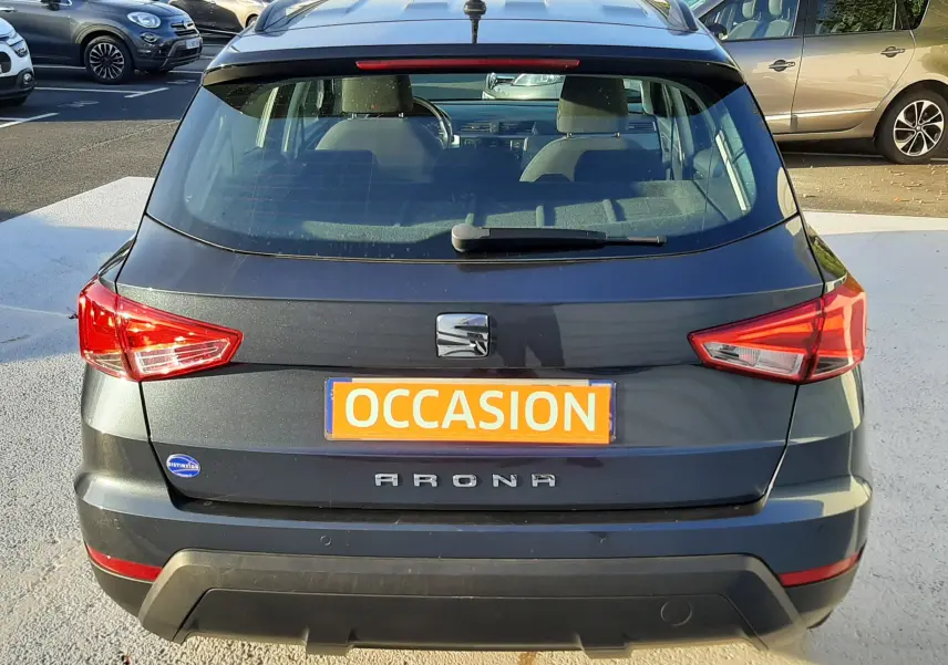 Vue arrière d'un SEAT Arona gris magnetic avec toit noir, immatriculé occasion, garé en extérieur.
