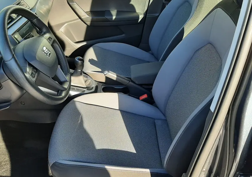 Vue intérieure côté conducteur de la SEAT Arona 2019, sièges tissu gris et volant multifonction noir.