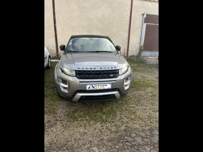 Vue de face d'un Range Rover Evoque gris Orkney garé devant un mur beige, avec calandre noire et logo visible.