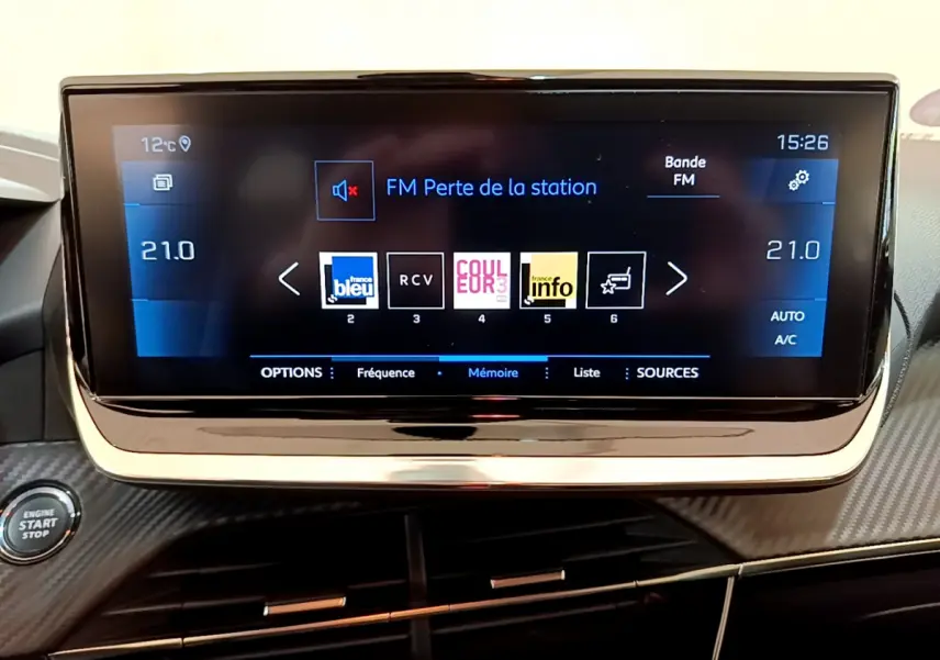 Écran tactile central de 7 pouces du tableau de bord de la Peugeot 208 gris clair, avec commandes climatisation et bouton start/stop visible.