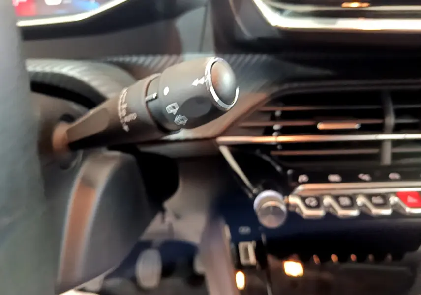 Gros plan sur la commande d’essuie-glace à gauche du volant dans l’habitacle gris clair de la Peugeot 208 2020.