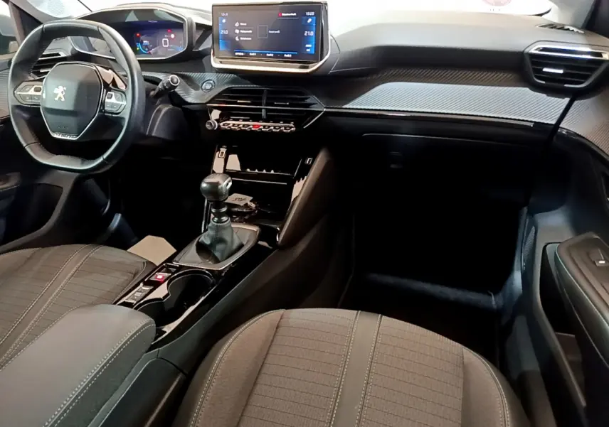 Intérieur de la Peugeot 208 PureTech 100 vue côté conducteur, tableau de bord moderne avec écran tactile et volant cuir.