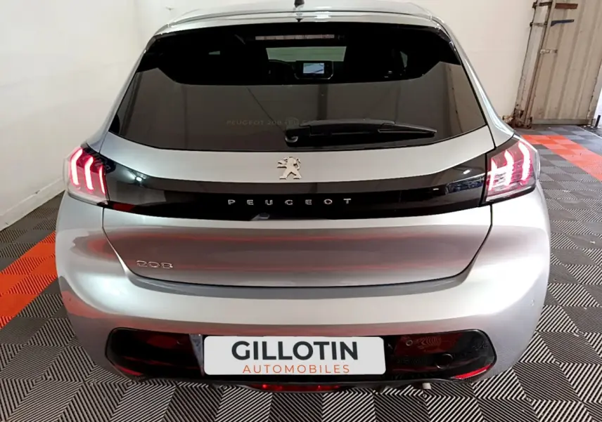 Vue arrière d'une Peugeot 208 gris clair avec feux LED allumés dans un garage.