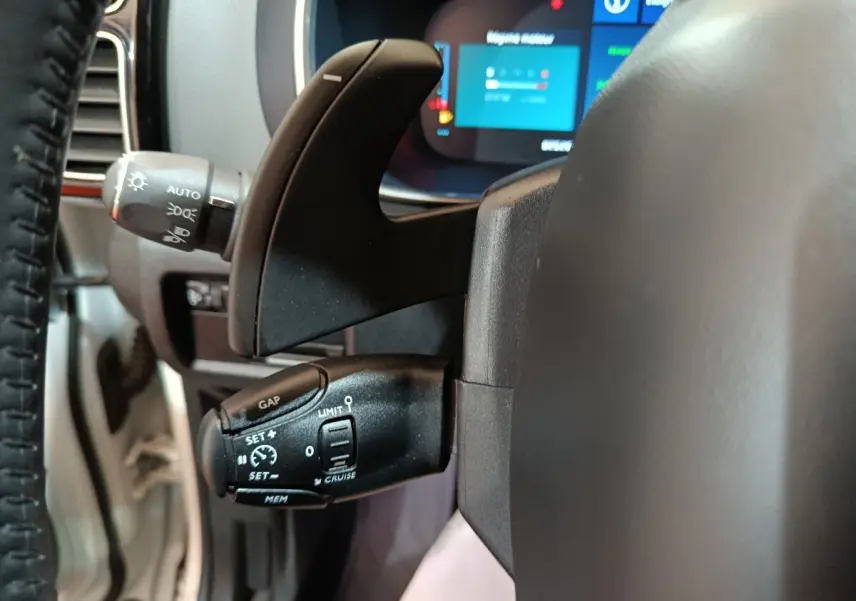 Gros plan sur la commande de régulateur de vitesse et palettes au volant d’un Citroën C5 Aircross blanc hybride rechargeable.
