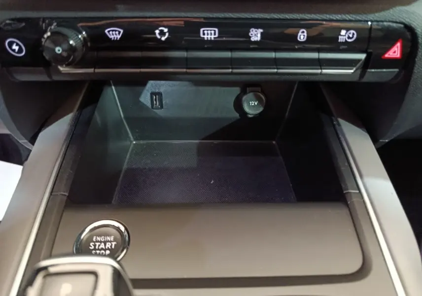 Vue rapprochée de la console centrale noire du Citroën C5 Aircross Hybrid avec bouton démarrage et prises USB et 12V visibles.