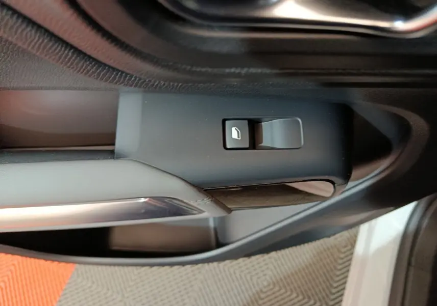 Gros plan sur le bouton de commande de vitre côté conducteur dans l’intérieur noir du Citroën C5 Aircross blanc hybride.