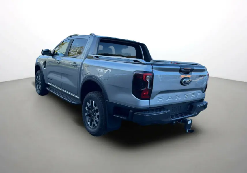 Ford Ranger 2.3 PHEV gris iconic vu en 3/4 arrière droit avec attelage et barres de toit visibles.