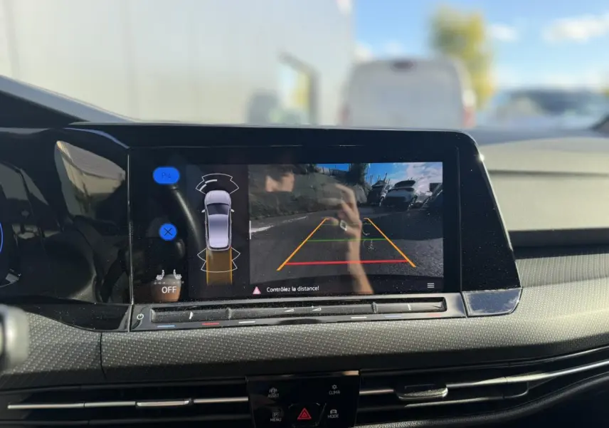 Vue intérieure centrée sur l'écran tactile affichant la caméra de recul de la Volkswagen Golf 8 noire de 2024.