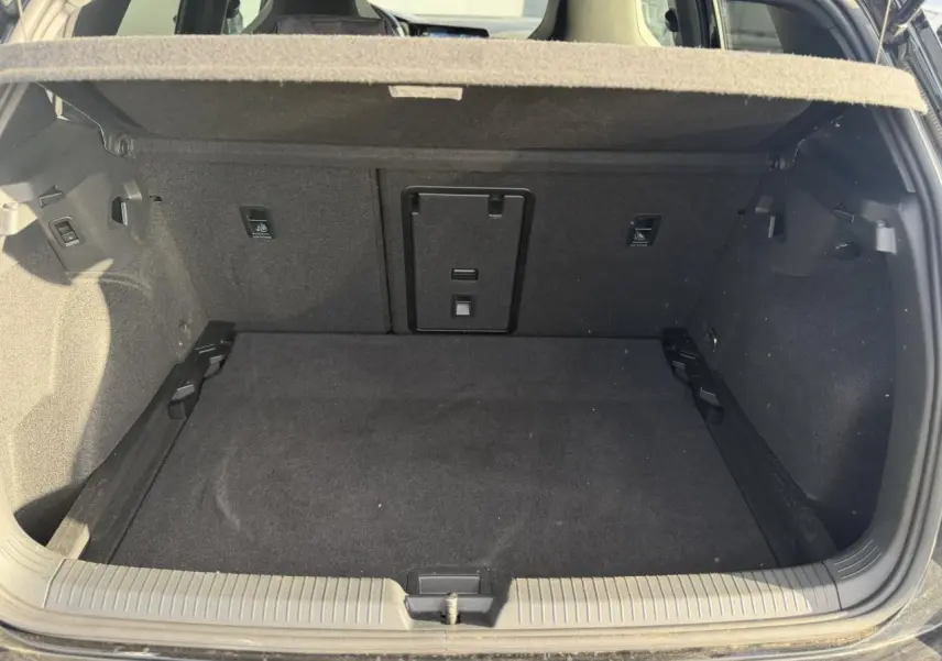Coffre ouvert vu de l'arrière d'une Volkswagen Golf 8 noire, montrant un espace de chargement vide et propre.