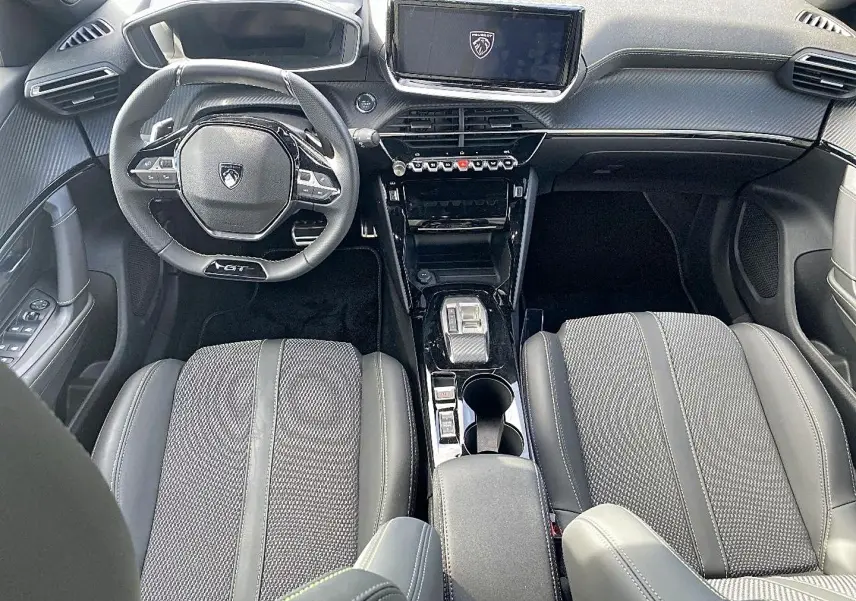 Vue intérieure avant du Peugeot 2008 noir 2025, avec volant GT, écran tactile et sellerie cuir tissu gris.