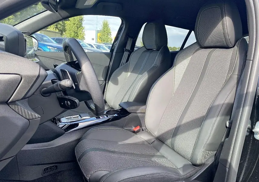 Vue intérieure côté conducteur du Peugeot 2008 noir 2025, montrant sièges en cuir et volant multifonction.