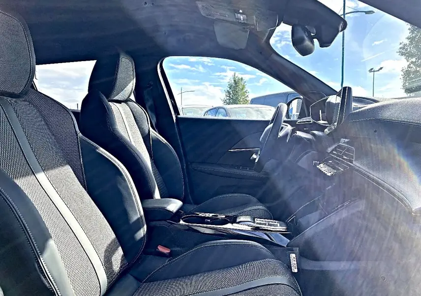 Vue intérieure côté conducteur du Peugeot 2008 noir 2025, mettant en valeur les sièges sport et le tableau de bord moderne.
