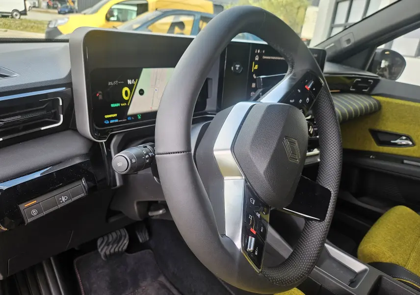 Vue intérieure du volant de la Renault R5 électrique 2025, avec tableau de bord numérique et sellerie jaune pop visible au fond.