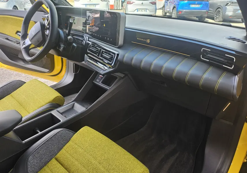 Intérieur avant droit de la Renault R5 Iconic 2025 avec sièges jaune pop et tableau de bord noir à surpiqûres jaunes.