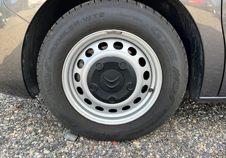 Gros plan sur la roue avant droite d'un Citroën Spacetourer gris 2022 avec jante acier et logo Citroën au centre.