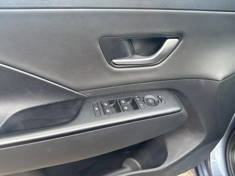 Vue rapprochée de la porte avant gauche noire avec commandes des vitres et rétroviseurs du Hyundai KONA Electric 2023 Metal Blue.