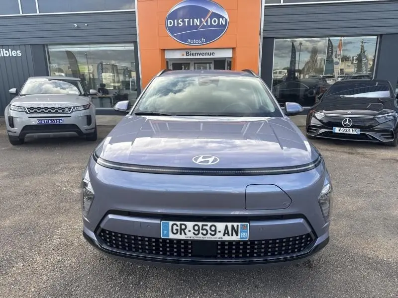 Vue avant d'un Hyundai Kona Electric 2023 Metal Blue métallisé, avec calandre fermée et logo Hyundai visible.