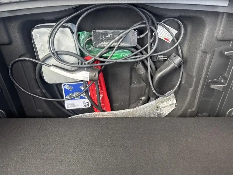 Vue du coffre avec câbles de recharge et accessoires du Hyundai Kona Electric 2023 Metal Blue métallisé.