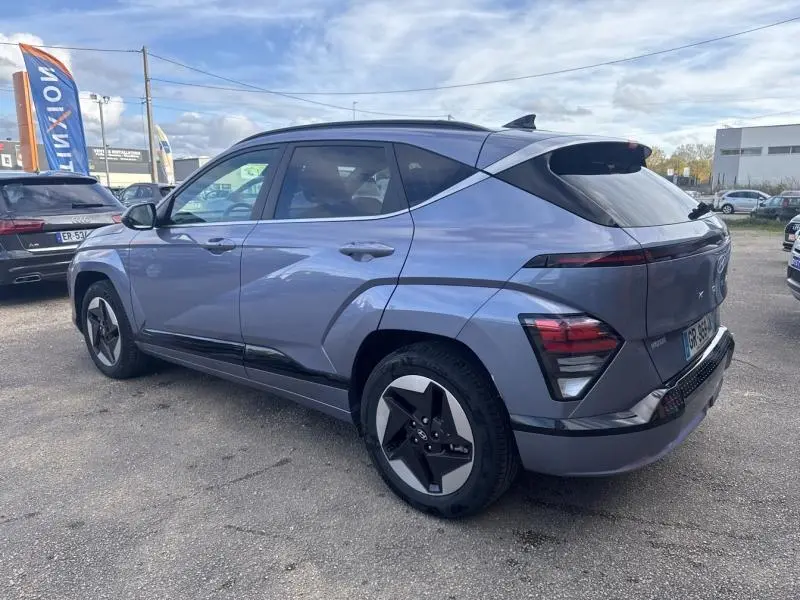Vue 3/4 arrière droite du Hyundai KONA Electric 2023 en Metal Blue métallisé avec jantes alu et feux LED distinctifs.