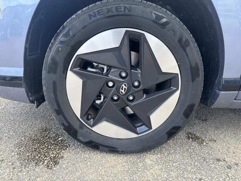 Gros plan sur la jante avant gauche du Hyundai Kona Electric 2023 en Metal Blue, avec design étoile noir et argent.