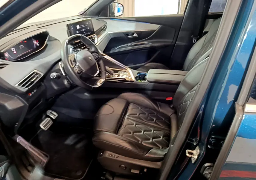 Vue intérieure côté conducteur du Peugeot 5008 bleu 2021, avec sièges cuir noirs et tableau de bord digital moderne.