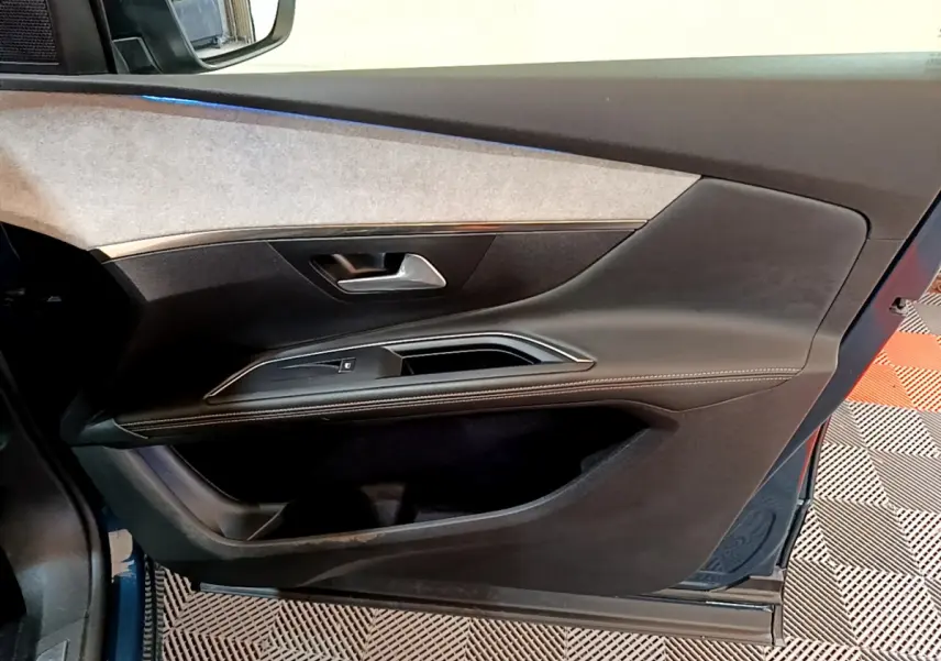 Vue intérieure côté gauche de la porte avant d'un Peugeot 5008 bleu avec garniture noire et grise élégante.