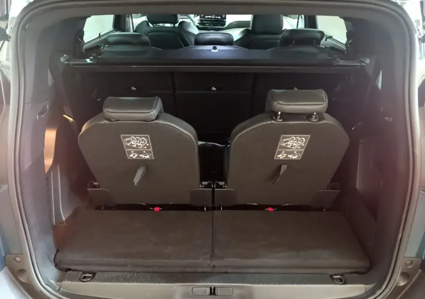 Vue arrière du coffre ouvert d'un Peugeot 5008 bleu 2021, montrant la 3ème rangée de sièges individuels rabattus.