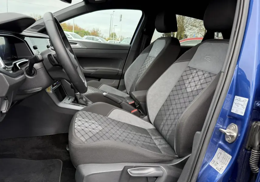 Intérieur côté conducteur d'une Volkswagen Polo bleu récif, sièges R-Line en tissu gris à motifs losanges.