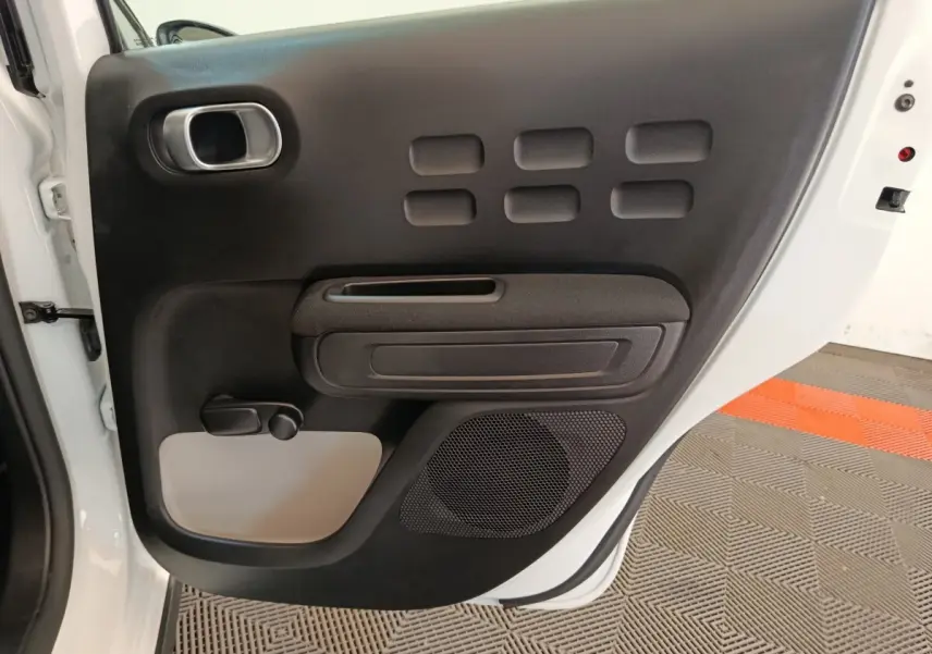 Vue rapprochée de la porte arrière gauche blanche d'une Citroën C3 2020 avec panneau intérieur noir et gris.