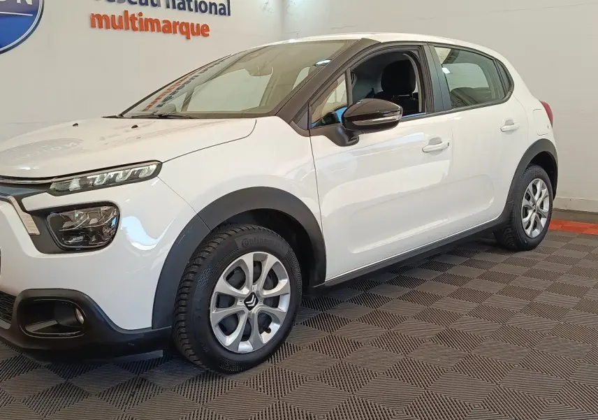Vue 3/4 avant droite d'une Citroën C3 blanche avec jantes alliage et rétroviseurs noirs dans un showroom.