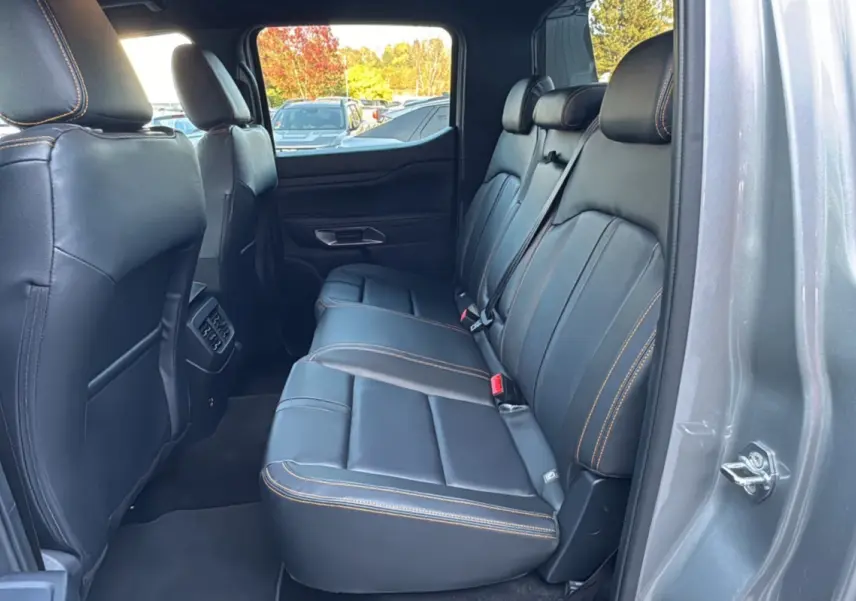 Vue intérieure côté droit des sièges arrière en cuir noir avec surpiqûres orange du Ford Ranger 2026 gris iconic Wildtrak Plus.