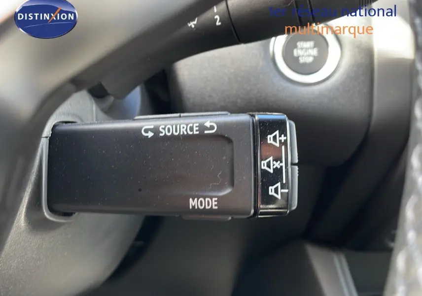 Gros plan sur la commande au volant du Renault Captur 2025, avec boutons source et mode visibles, intérieur noir.
