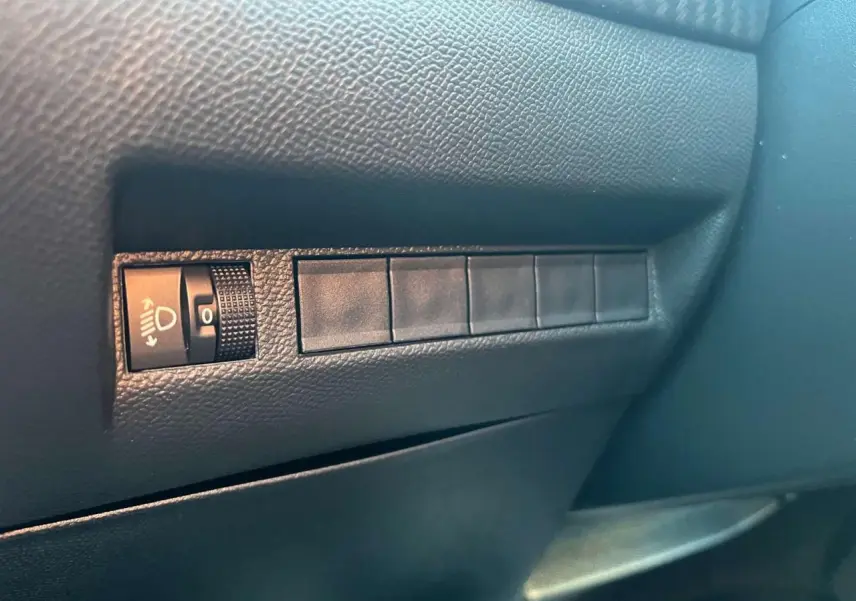 Détail du tableau de bord côté gauche du Peugeot 2008 2024 bleu Vertigo Metal avec réglage des phares.