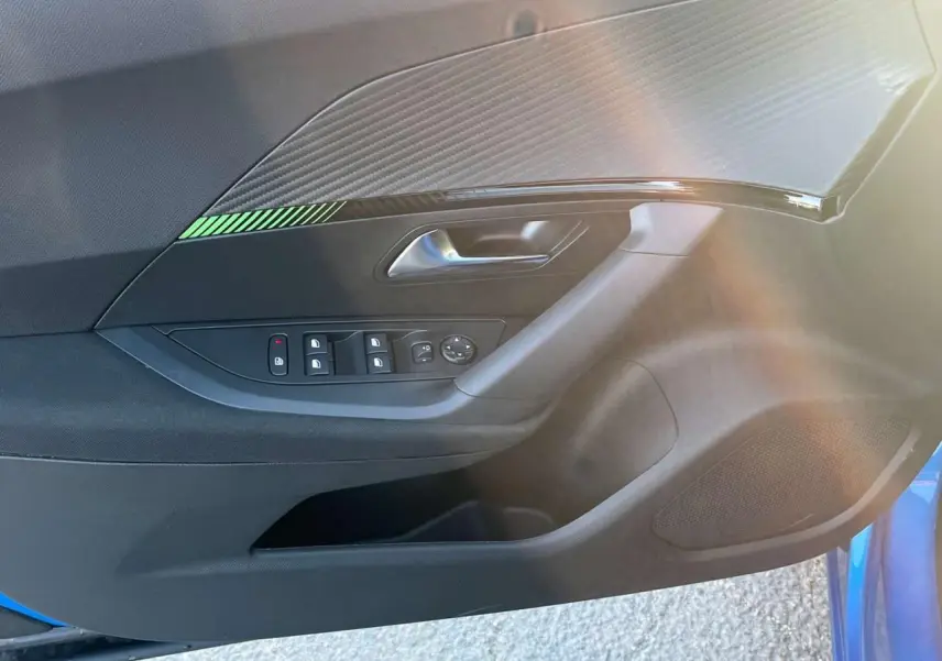 Panneau de porte côté gauche du Peugeot 2008 2024 bleu Vertigo Metal avec commandes de vitres et décor carbone vert.