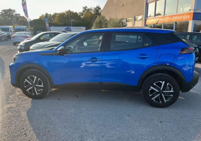 Profil côté gauche d'un Peugeot 2008 2024 bleu Vertigo Métal avec jantes noires et toit noir contrasté.