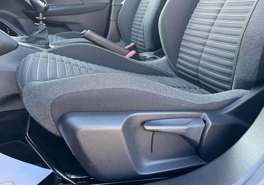 Gros plan sur le siège avant droit du Peugeot 2008 2024, tissu noir avec surpiqûres vertes, levier de réglage manuel visible.