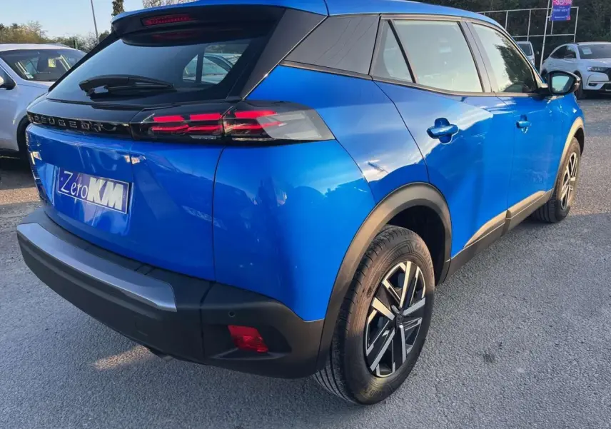 Vue 3/4 arrière droite d'un Peugeot 2008 2024 bleu Vertigo Metal avec toit noir et jantes alliage distinctives.