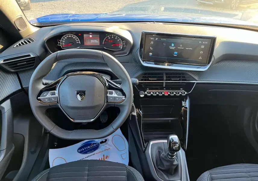 Vue intérieure du tableau de bord du Peugeot 2008 2024 avec volant compact, écran tactile et levier de vitesse manuel.