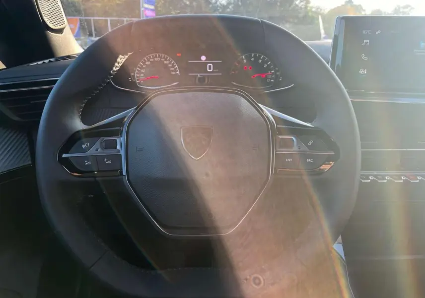 Vue rapprochée du volant multifonction noir du Peugeot 2008 2024 avec tableau de bord numérique et écran tactile.