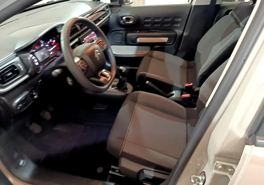 Intérieur de la Citroën C3 beige 2022 vu côté conducteur, avec tableau de bord numérique et sièges gris foncé.
