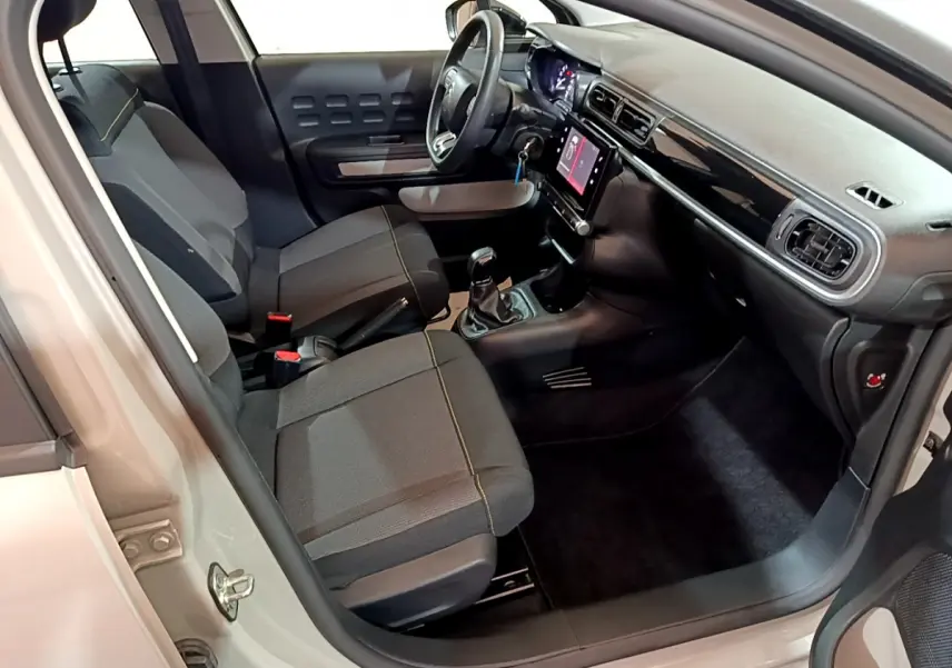 Intérieur de la Citroën C3 beige vue côté conducteur, montrant sièges noirs et tableau de bord avec écran tactile.
