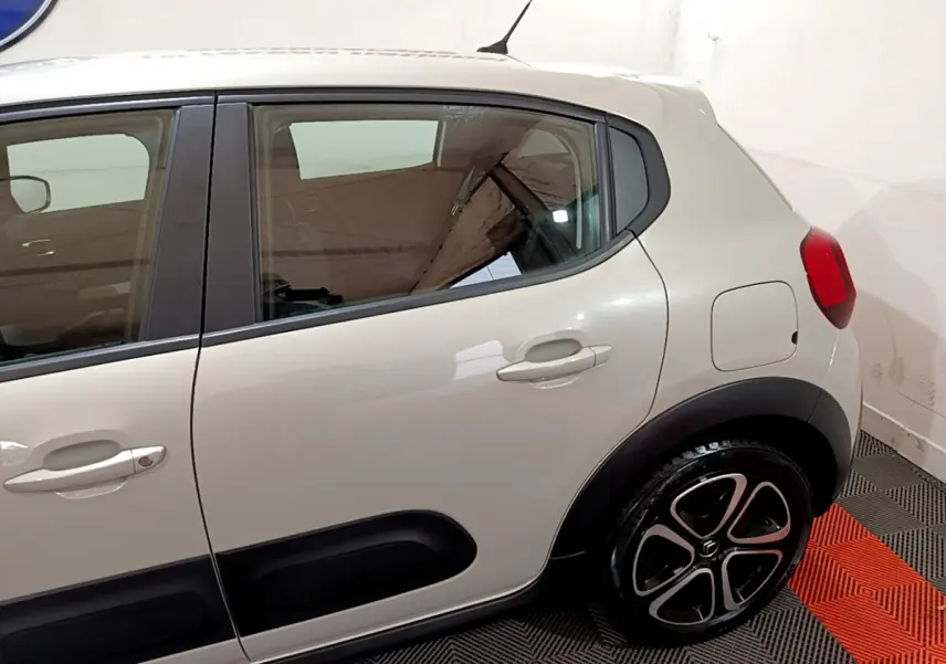 Vue latérale côté droit d'une Citroën C3 beige 2022 avec protections noires sur les portières et jantes stylisées.