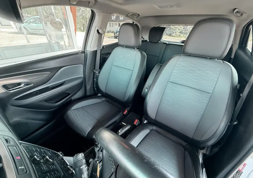 Vue intérieure avant de l’Opel Mokka X 2016, sièges tissu et cuir gris noir avec détails de la console centrale.